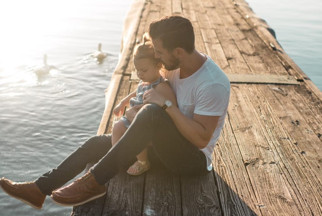 kids and daddy siting on bridge