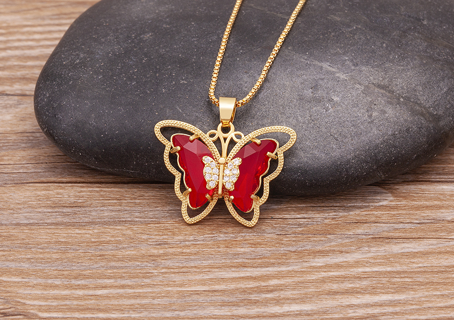 red butterfly pendant lying on stone